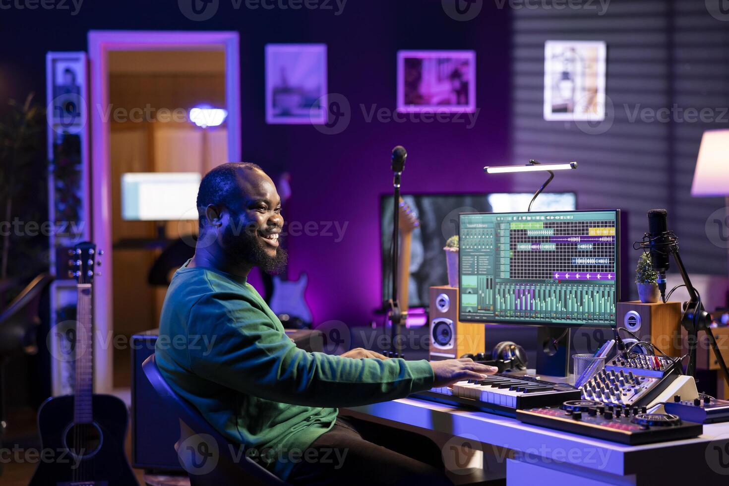 Male artist producing music on electronic piano keyboard in home studio. Sound engineer playing MIDI controller, recording and composing a soundtrack with acoustic tools and gear. photo
