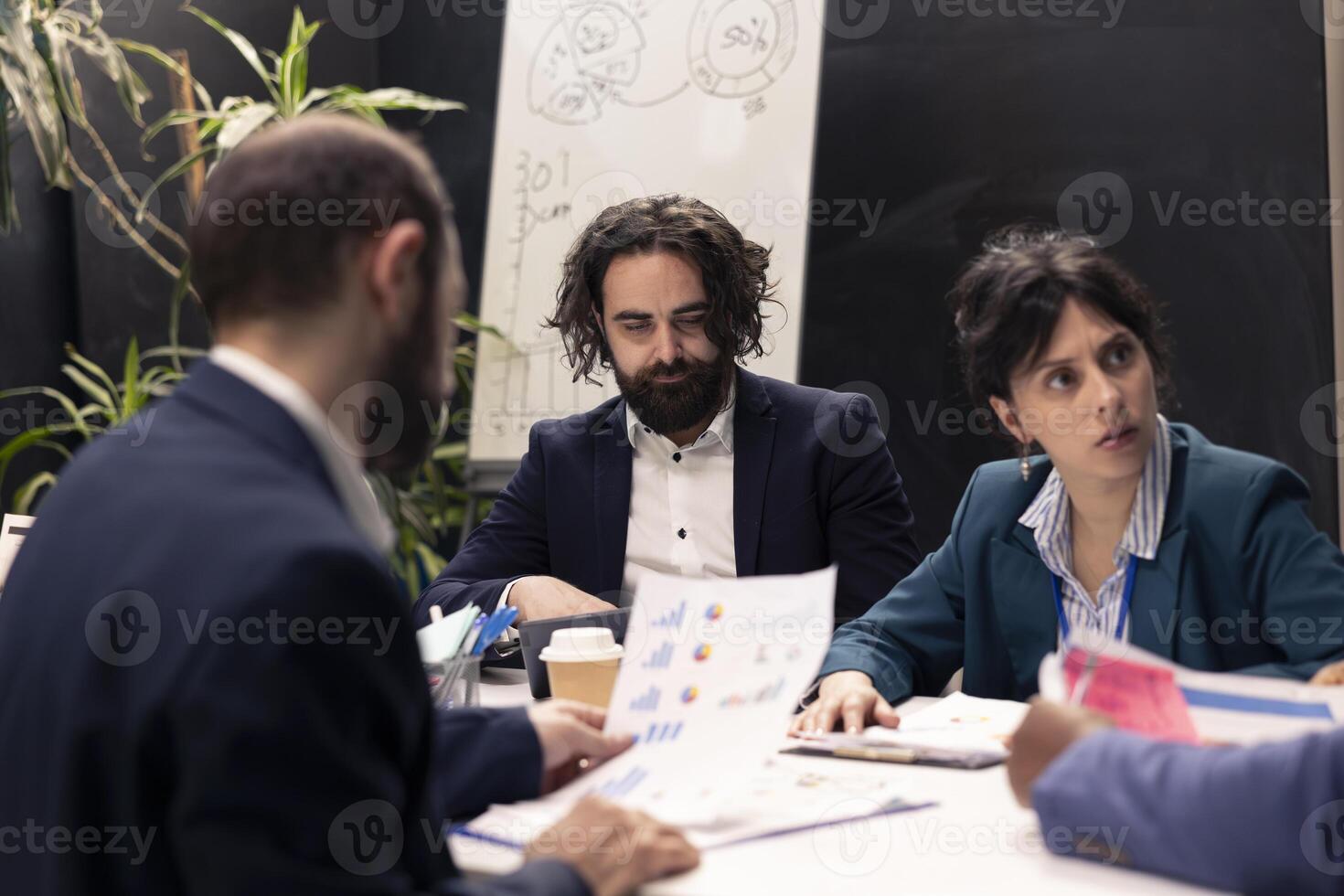 Project manager and his team gathering in a boardroom meeting, discussing all important statistics, giving insight and details to staff members before working on development planning. photo
