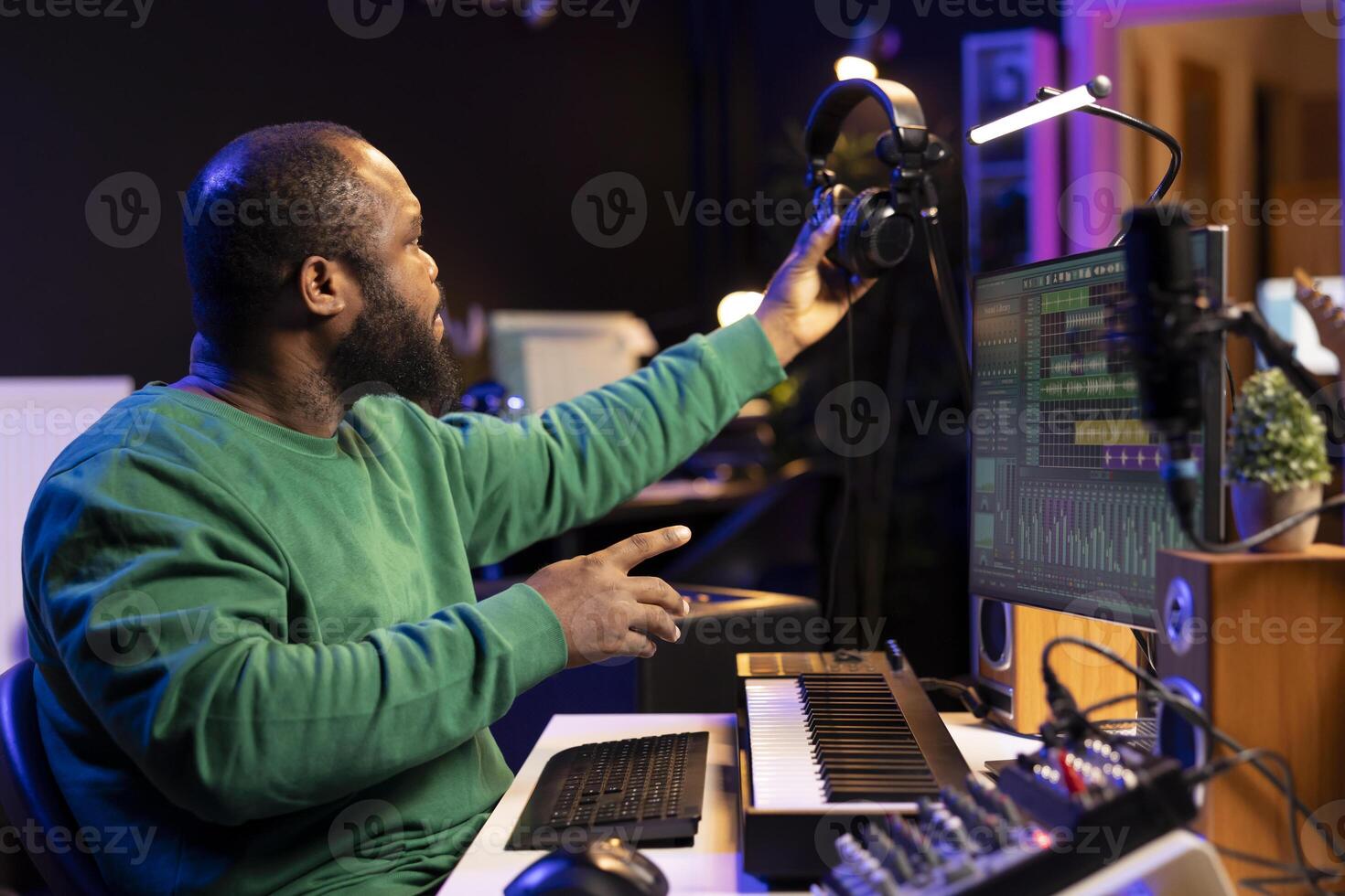 Audio technician works with recording tools in his home studio, using mixing console and pre amp knobs to add sound effects on tracks. Composer editing new tunes in post production. photo