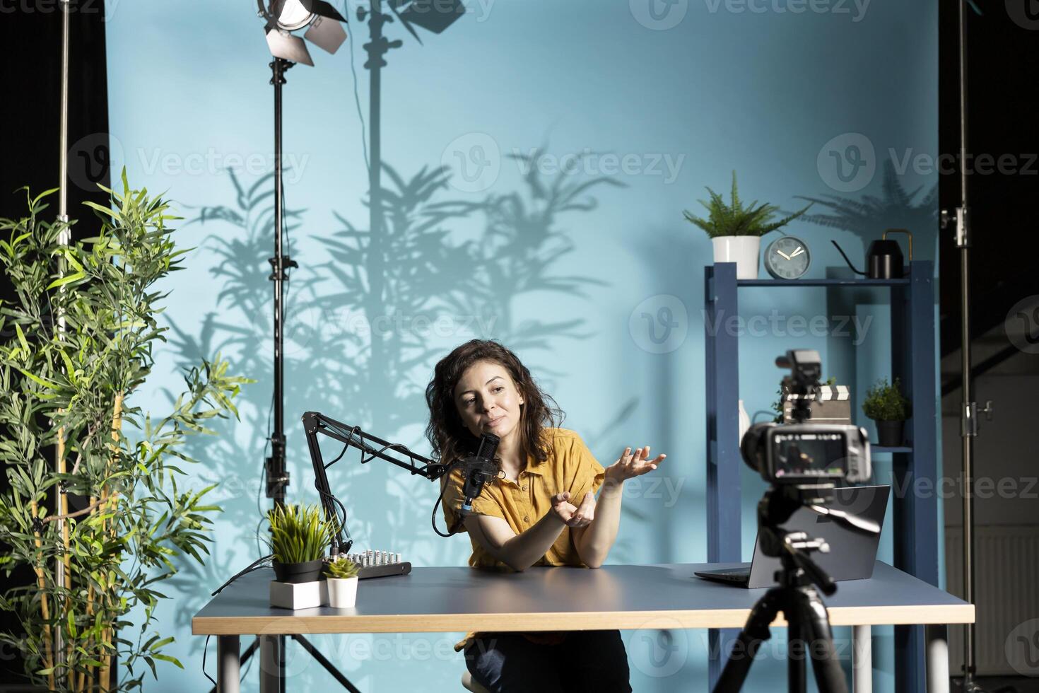 Influencer hosting internet show, speaking into professional mic, recording live stream with camera. Content creator smiles while engaging with audience, discussing in high tech workspace photo