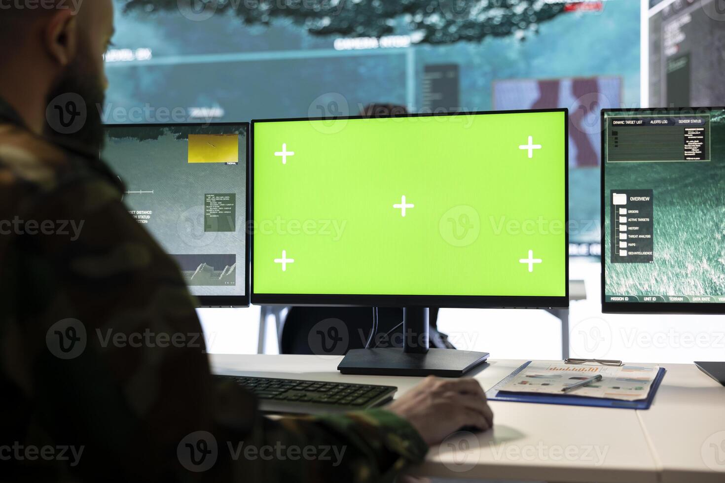 Soldier working on reconnaissance CCTV imagery on pc next to green screen, tracking troops in the field. Army trooper in control center headquarters, satellite government data. photo