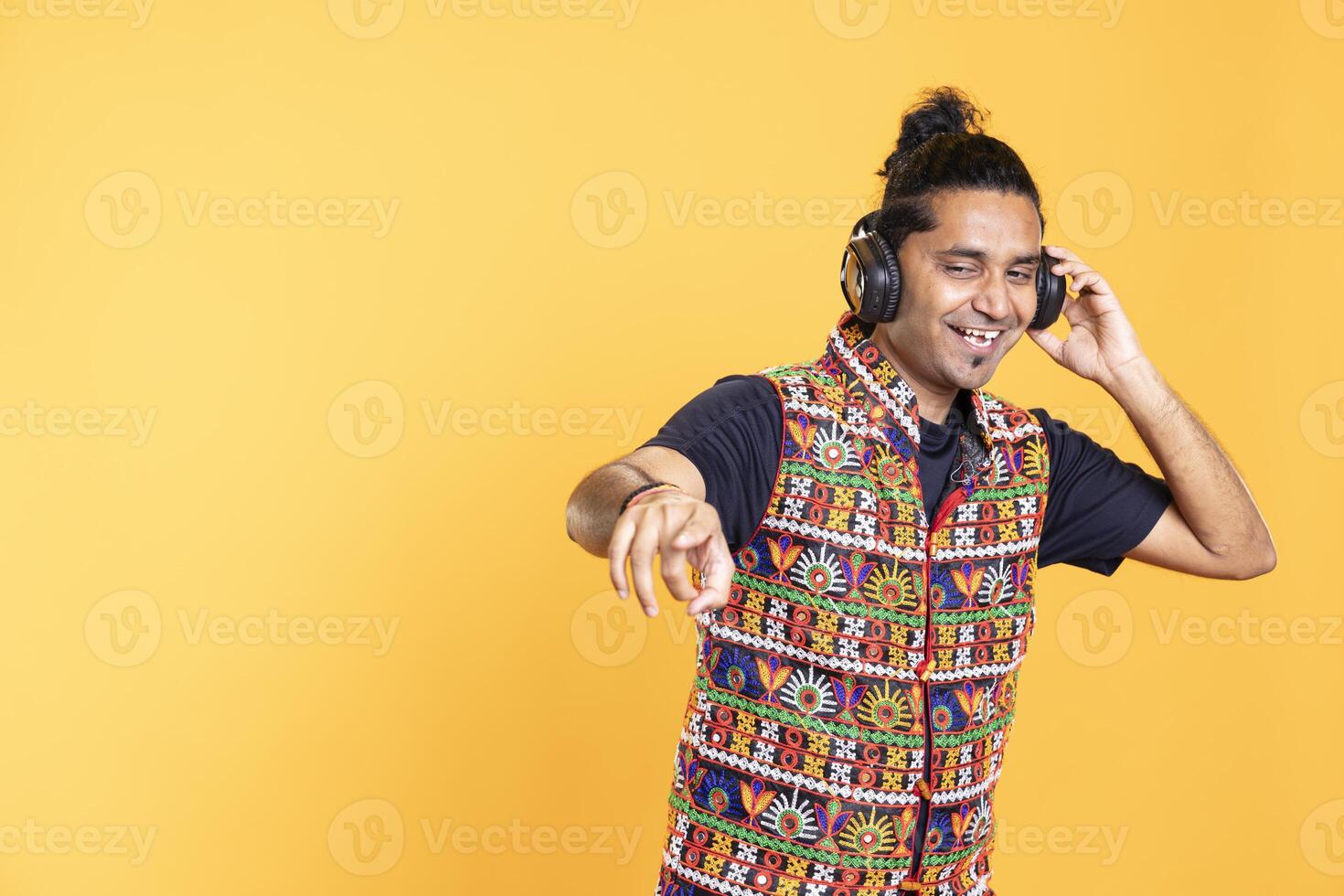 Joyful person wearing headphones having fun, dancing on music, enjoying leisure time. Jolly man entertaining himself doing energetic movements on songs, isolated over studio background photo