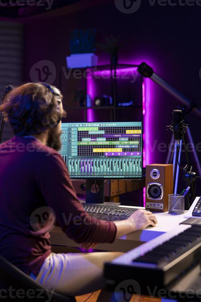 Audio engineer operates mixing equipment and oversees recordings performances to ensure the perfect tunes. Artist producer composing sounds with MIDI controller piano and electronic console. photo