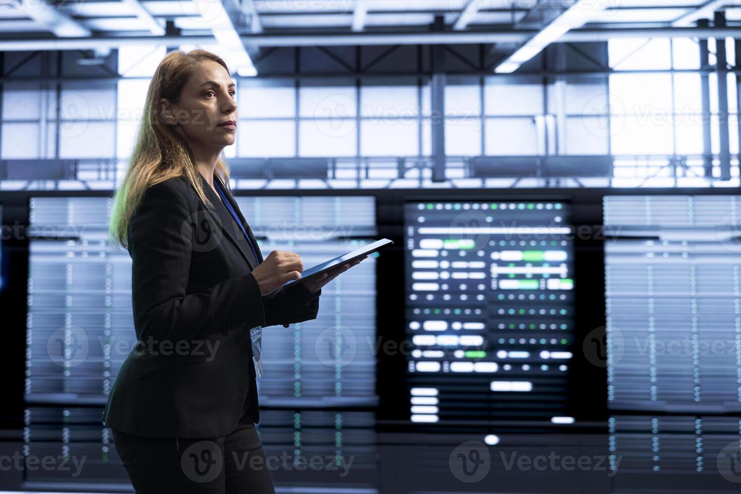 Manager in server room using tablet to implement and maintain security measures, protecting systems from unauthorized access. Woman in data center doing hardware maintenance with device photo