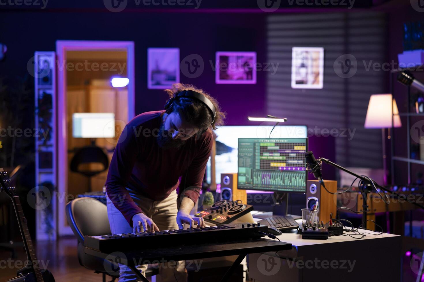 Cheerful artist playing music on electronic keyboard in home studio, recording new songs and having fun with audio session. Confident musician plays tunes on piano midi controller. photo