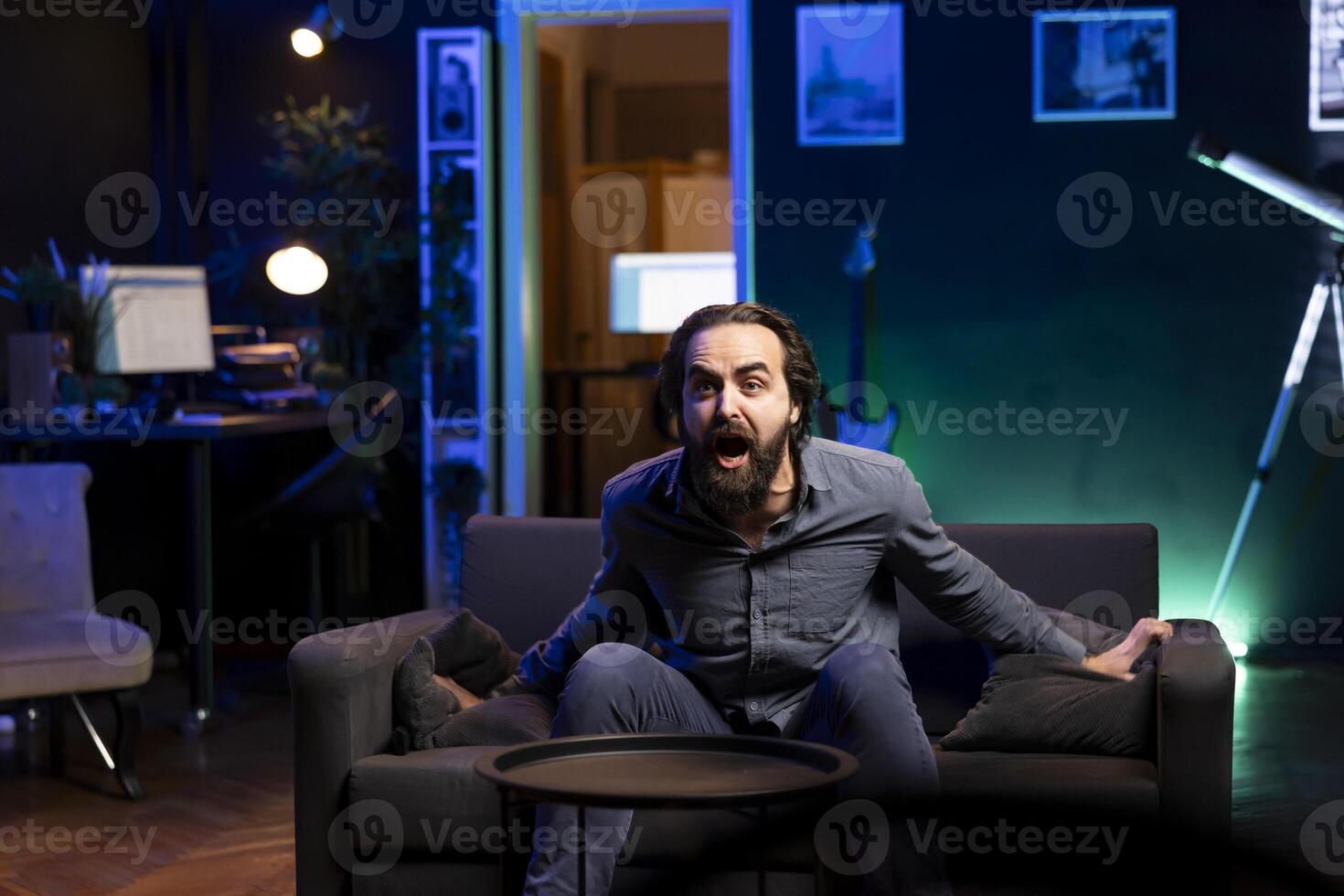 Ecstatic sports fan watching live match broadcast in apartment, shouting to celebrate favorite team scoring. Euphoric man yelling, delighted about goal, happy with own country triumph in tournament photo