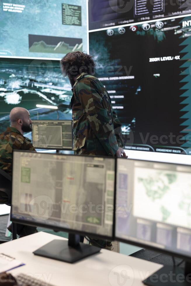 Military staff overseeing intelligence gathering activity to offer support to infantry unit in the field, ensuring national safety and defense. Trooper coordinating recruits team in control room. photo