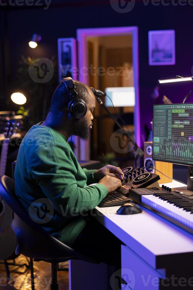 Skilled music producer composing new soundtracks on console and daw software, working with stereo gear in home studio. Young artist engineer uses pre amp knobs, signal processing. photo