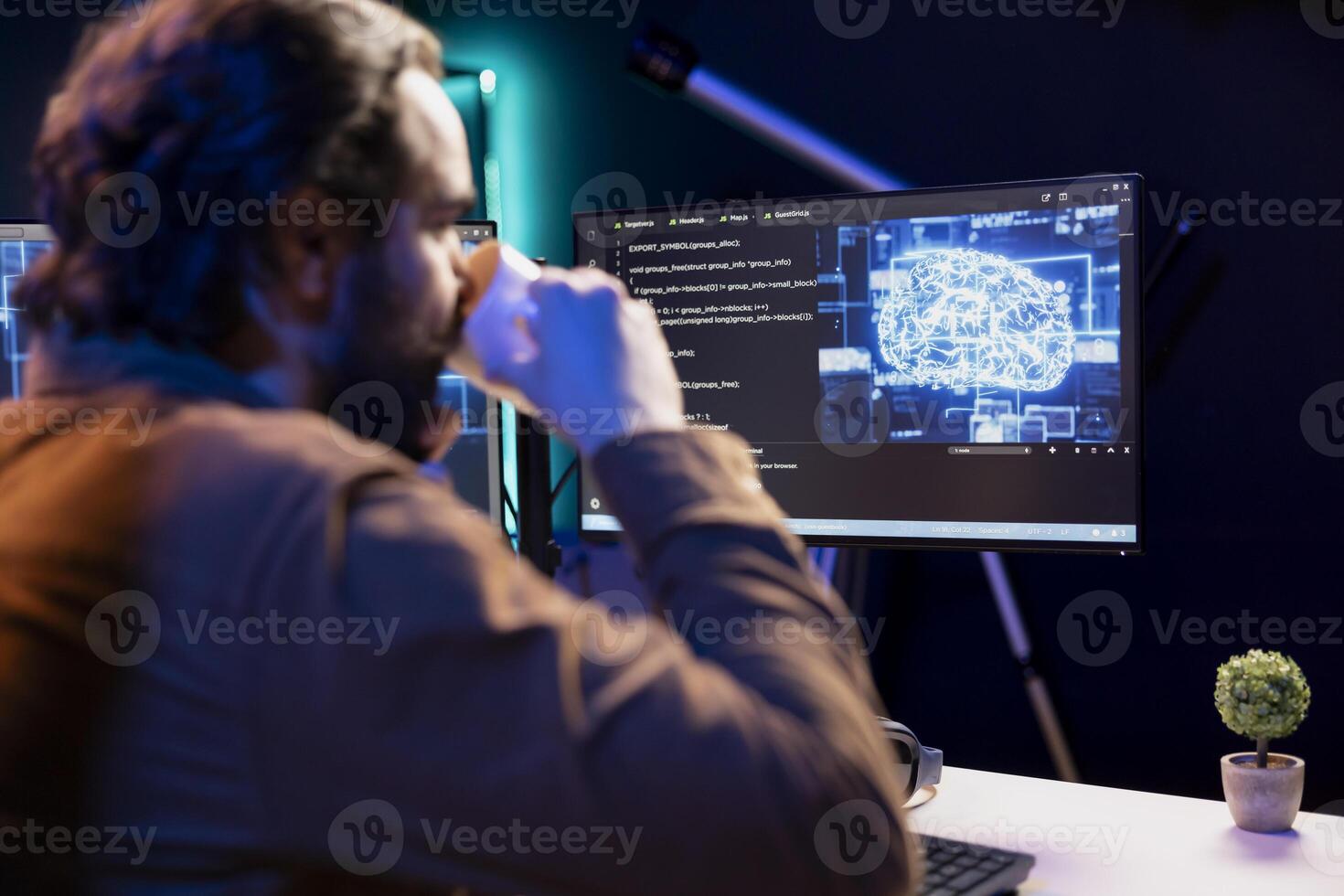 Programmer drinking coffee and doing maintenance on artificial intelligence neural networks computerized model. Tech support expert enjoying hot beverage while checking up on AI systems photo