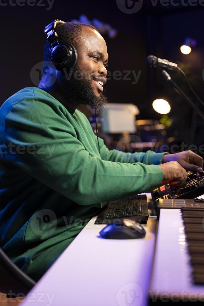 Audio engineer with headset mixing and mastering his recorded files, operating on a professional soundboard in home studio. Artist producer composing new tracks with sound effects. photo