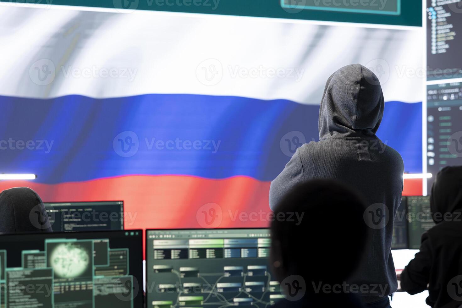 Russian hacker with a hood installing panic by misconception and manipulation, working in governmental cyber operations room. Impact of fake news and ideology propaganda in a hybrid war. photo