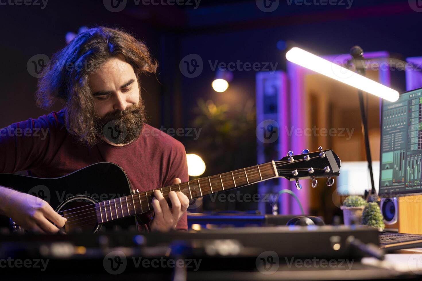Songwriter musician recording sounds on daw software with guitar, enjoying leisure time in home studio office. Audio engineer and producer creating new songs, electronic mixing instruments. photo