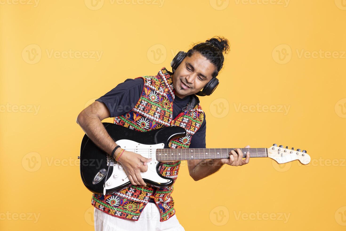 Smiling rocker playing rock music with electric guitar, isolated over studio backdrop. Ecstatic man excited to use musical instrument, having fun doing concert, producing entertaining songs photo