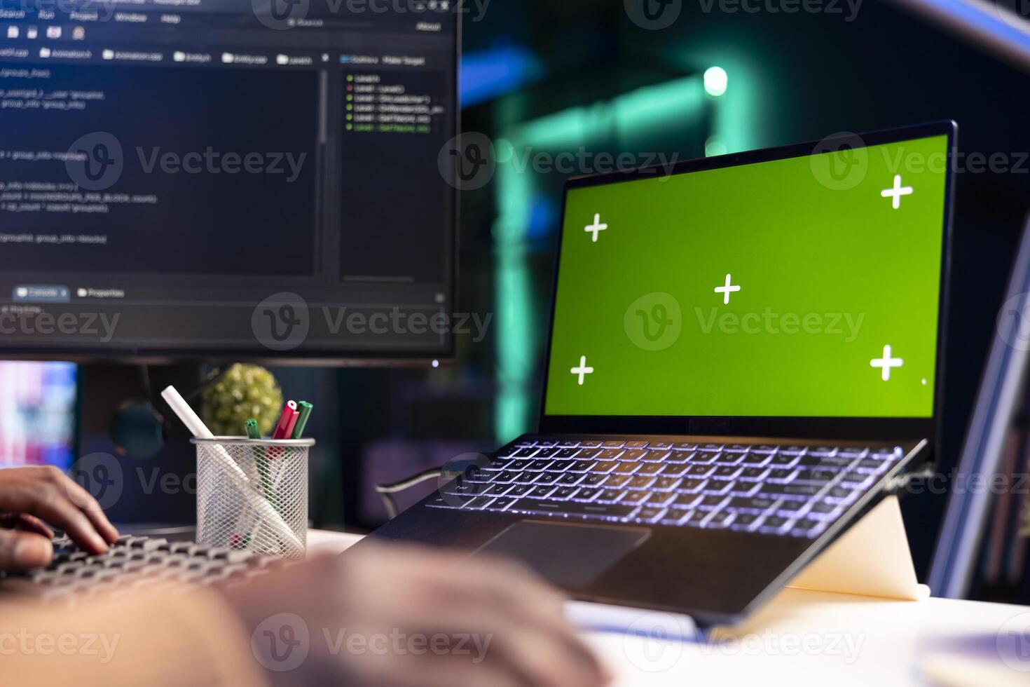 African american programmer working on cloud computing next to green screen, writing code for optimization on terminal window. IT engineer works to insert html code, server security. photo