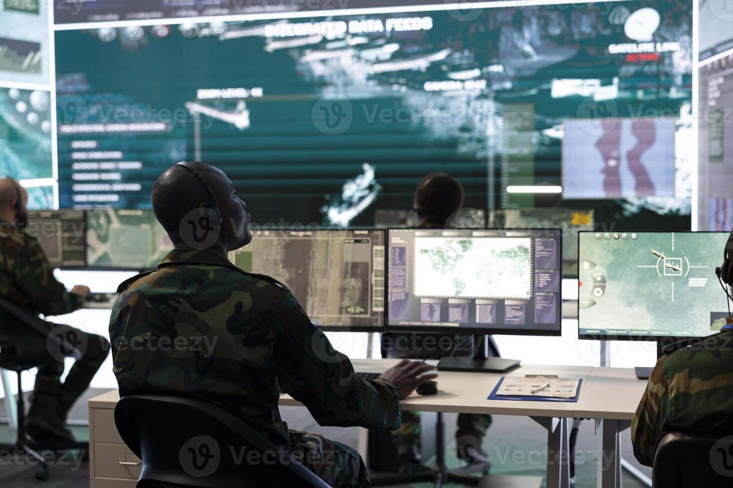 Military personnel examining surveillance footage captured by CCTV satellite, looking at a big screen in control center. Troopers ensuring national safety by operating reconnaissance system. photo