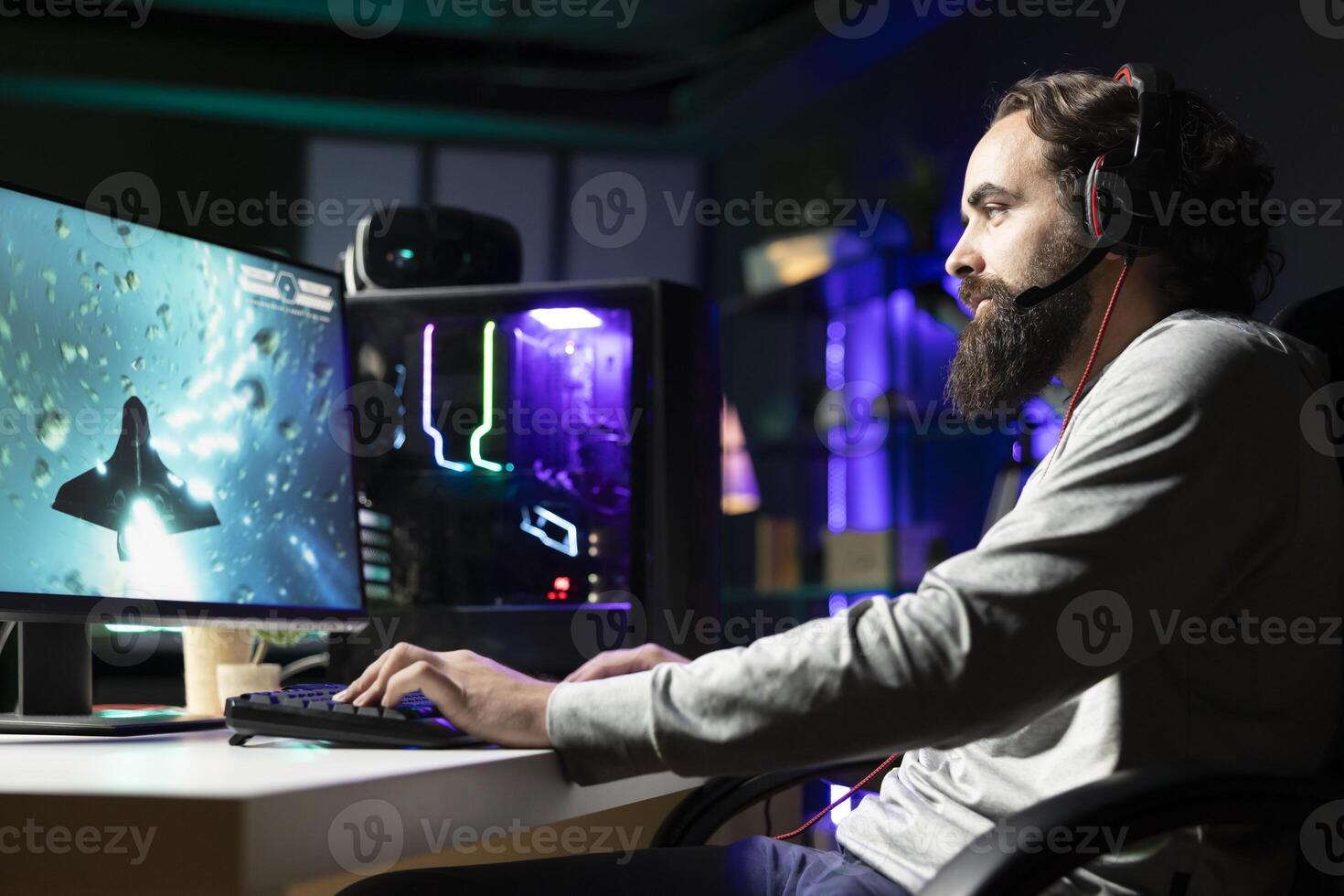 Man using gaming keyboard and headphones to play spaceship flying game with overlay HUD showing health, fuel bars. Gamer wearing headset navigating with spacecraft in galaxy, shooting at asteroids photo