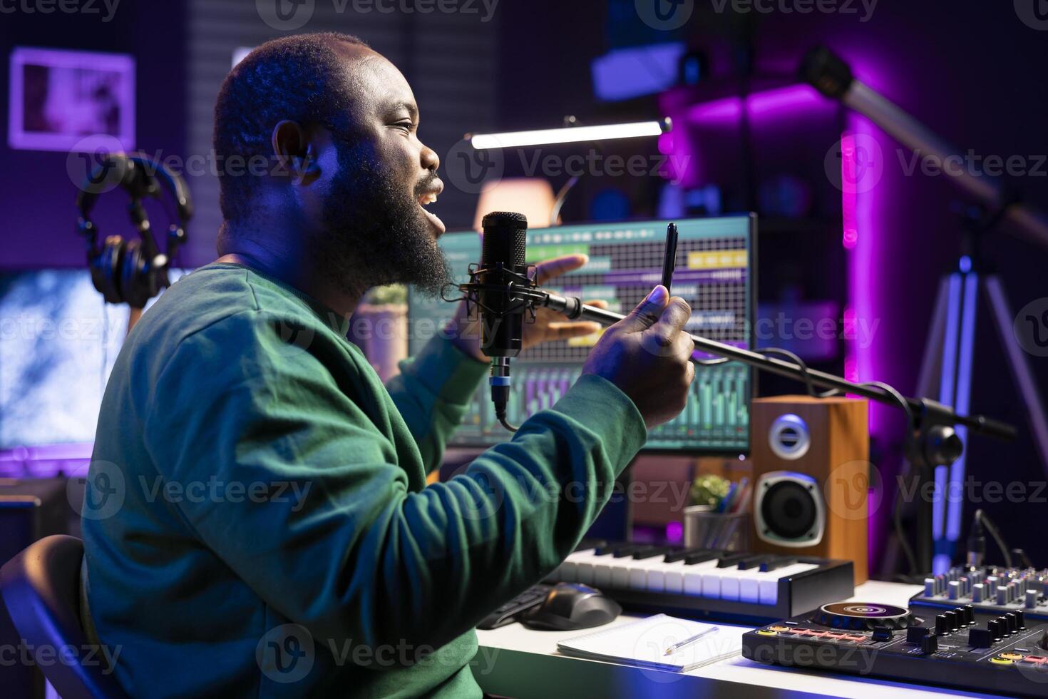 African american composer recording audio files on his song, adding special effects and editing with a mixing console to improve sound quality. Male artist songwriter performing on microphone. photo