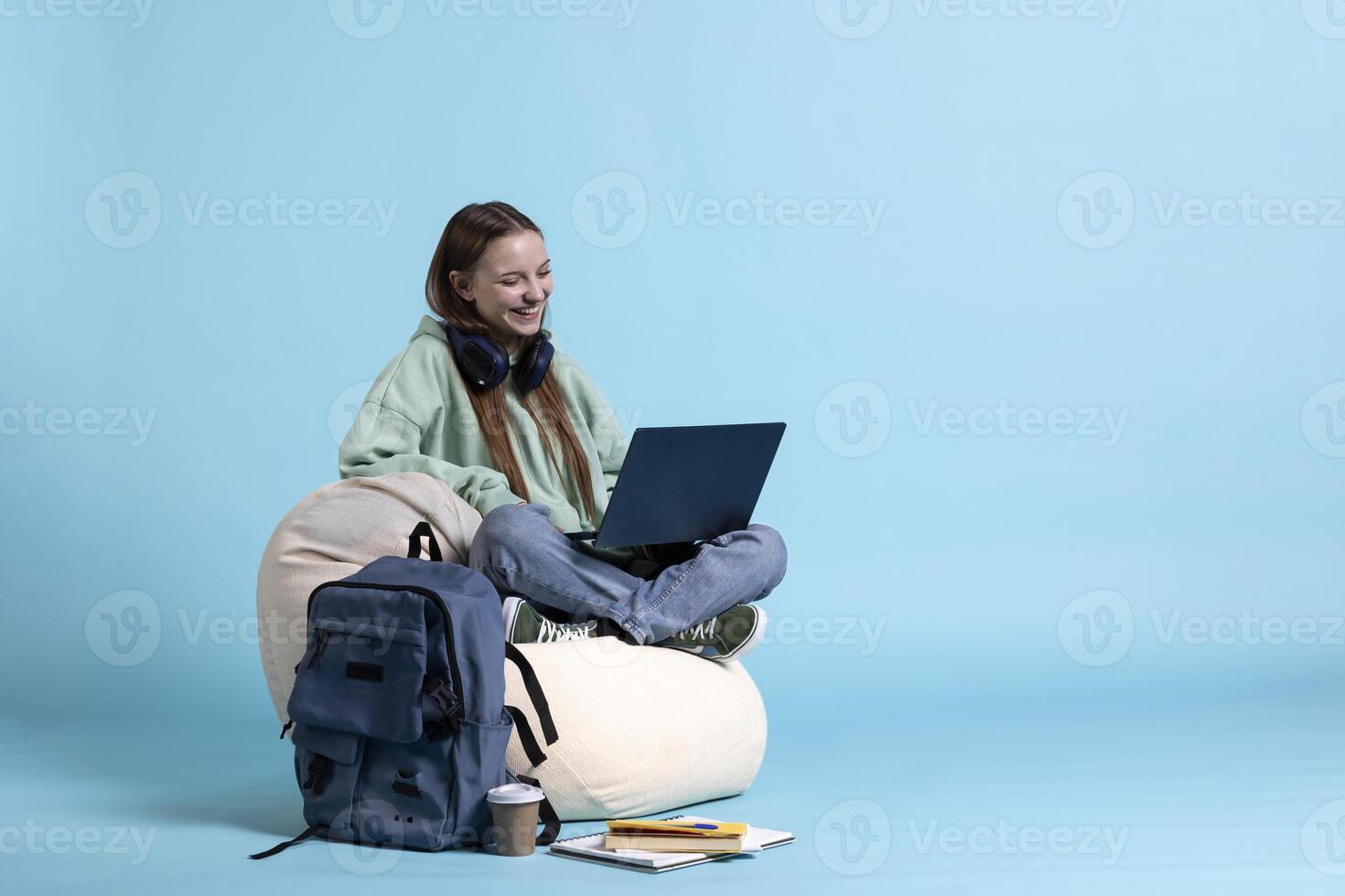 Radiant woman laughing while talking with friends during teleconference meeting using laptop, studio background. Teenager having fun catching up with mates during online videocall, being amused photo