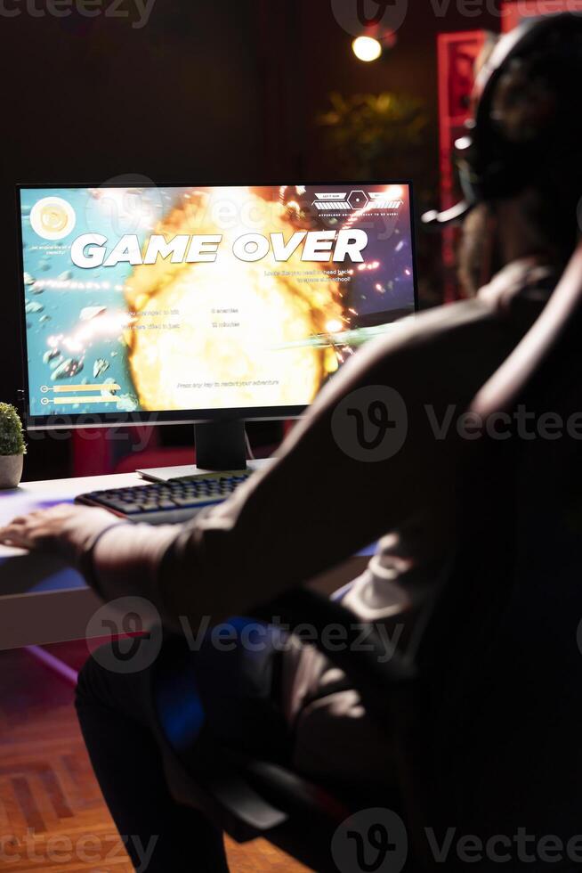 Upset gamer having to restart game from beginning after losing mission while playing spaceship videogame. Player feeling gutted after getting flying spacecraft destroyed by more powerful enemies photo