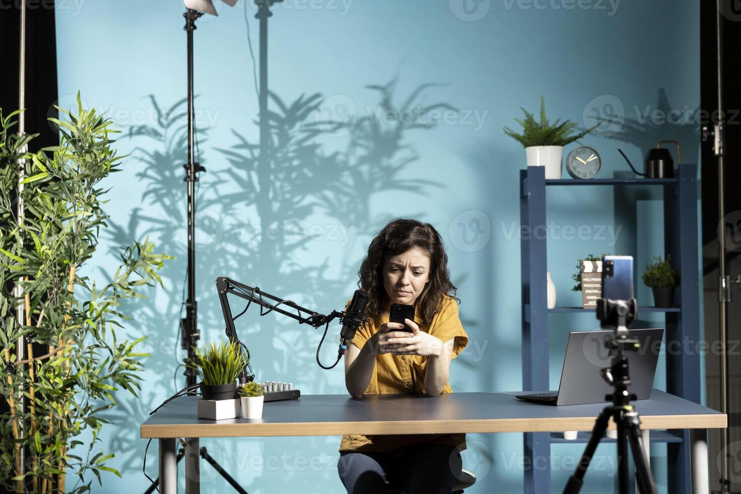 Unhappy woman frowning after receiving upsetting text messages while filming for online channel. Disappointed internet star sulking after receiving bad news, looking at mobile phone screen photo