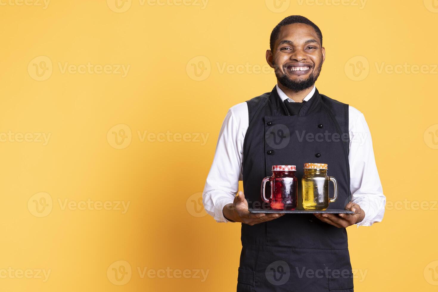 Waiter bringing drinks in glasses on a tray for clients at a table, serving lemonade to customers before their dinner. Professional staff serving people at a five star restaurant. photo