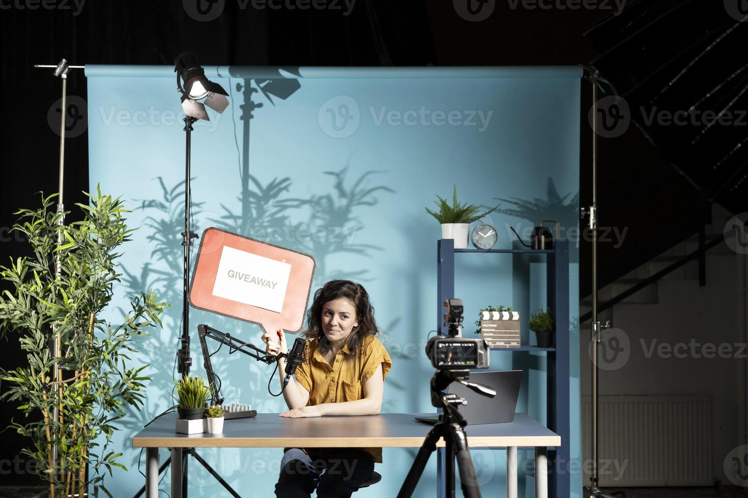 Social media content creator promoting giveaway with red cardboard sign, filming with specialized gear. Vlogger running contest, advertising it with copy space board, filming with professional camera photo