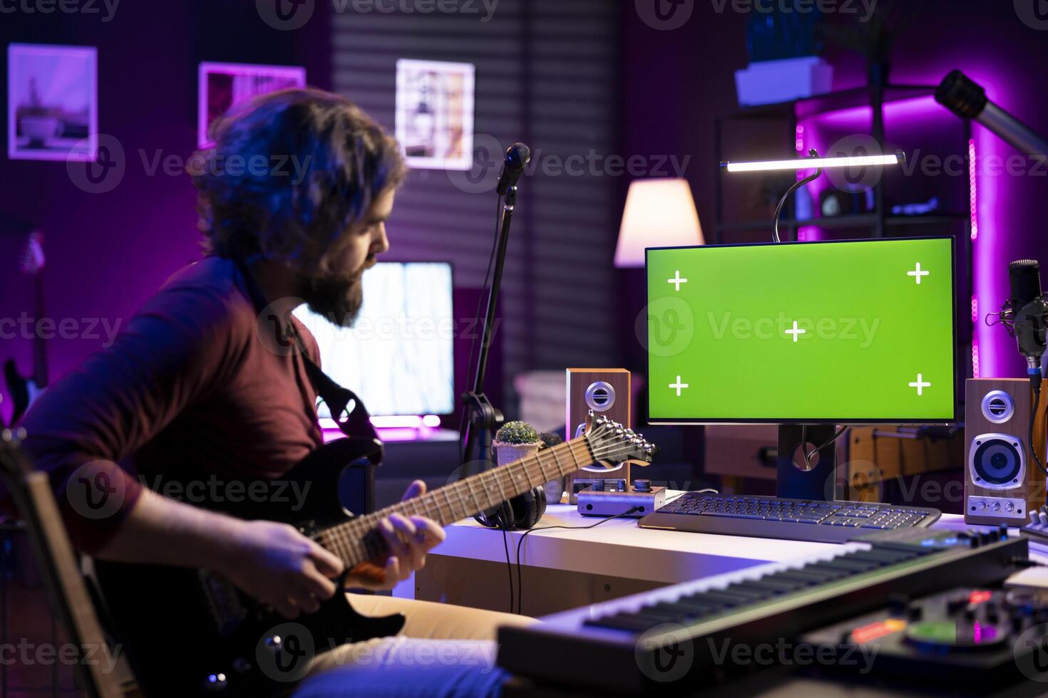 Artist playing acoustic guitar and following tutorials online on computer that shows greenscreen display. Music producer learning new instrument and accords to record tunes on daw software. photo
