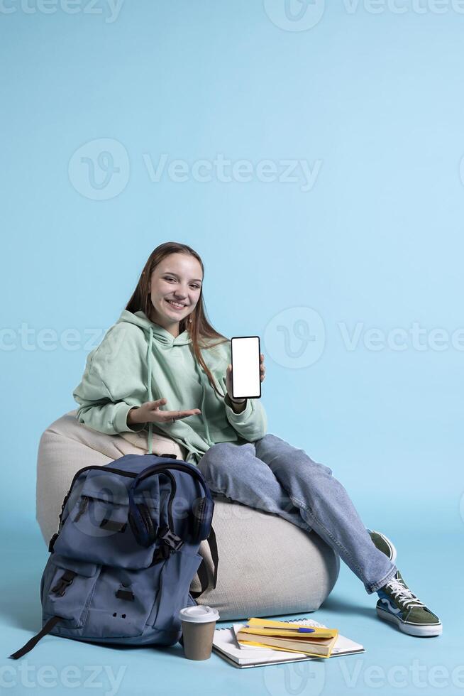 Smiling woman presenting mobile phone with isolated screen display, doing advertisement, studio background. Joyous person creating ad promotion with mockup smartphone device photo