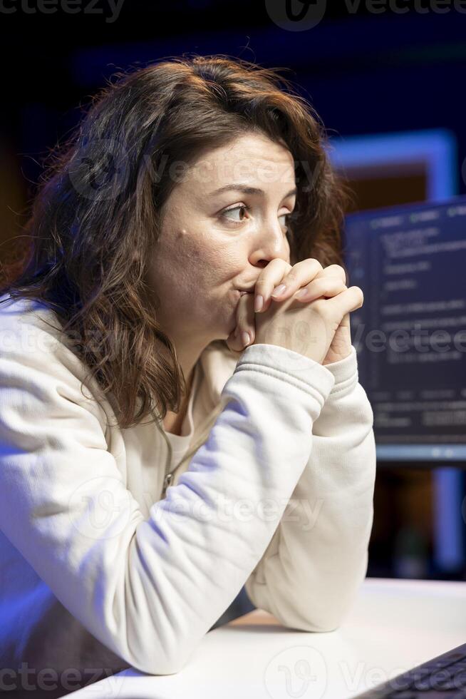 Cybersecurity professional anxiously looking at computer screen, trying to find company security loopholes and injected viruses. Programmer carefully reading lines of code on desktop PC monitor photo