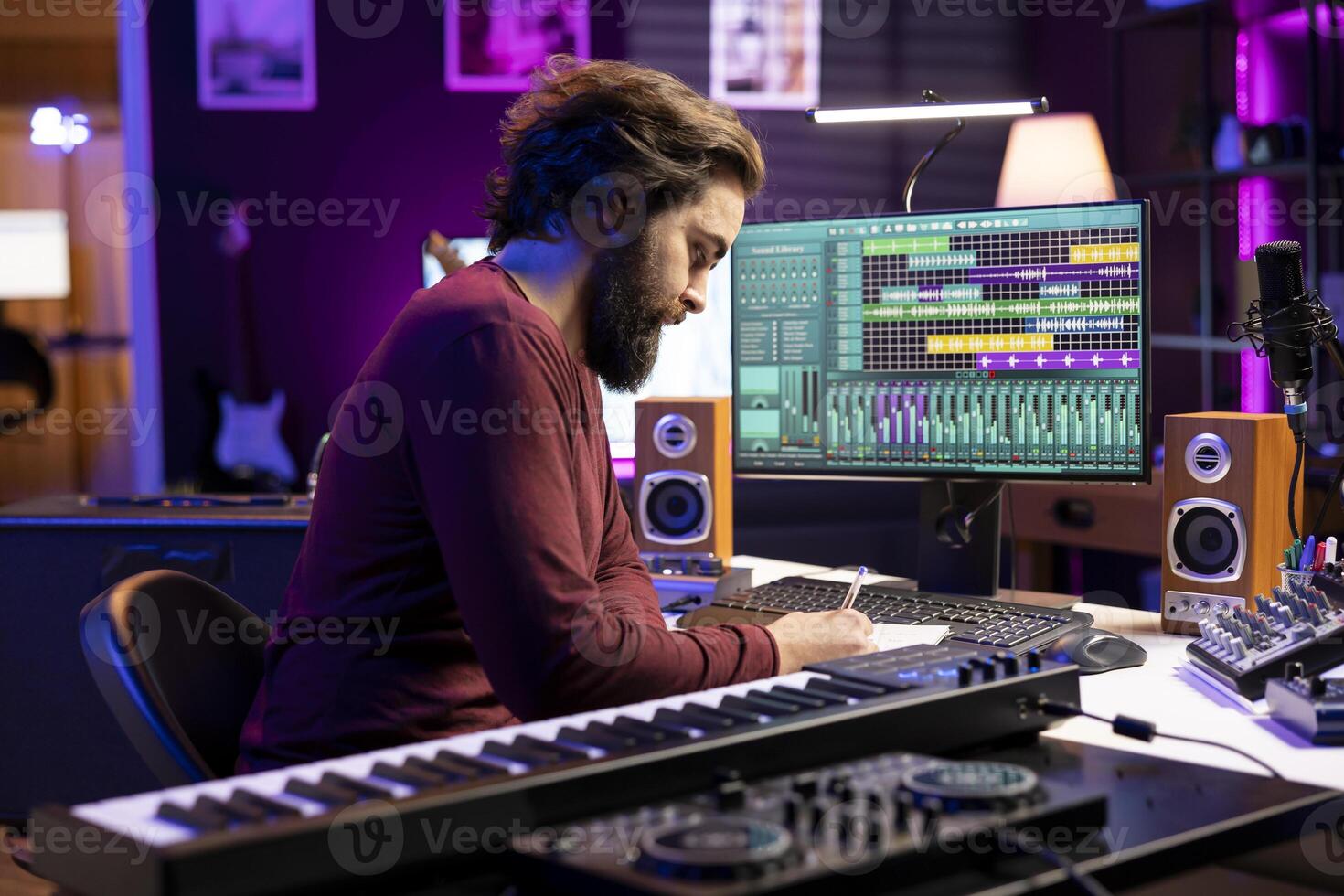 Musical producer composing new lyrics for songs and recording music with audio devices in home studio. Singer songwriter writes material by taking notes and creating rhymes or melodies. photo