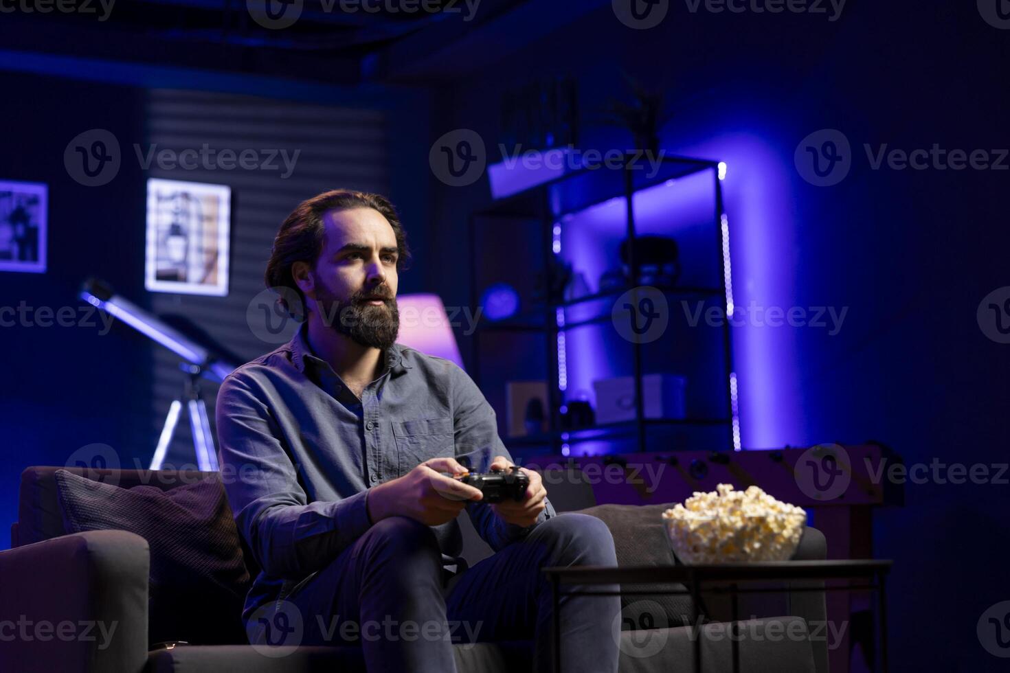 Gamer engaging in online competitive multiplayer tourney using cutting edge gaming console and gamepad. Man in home theatre playing engaging videogame, focused on defeating enemies photo