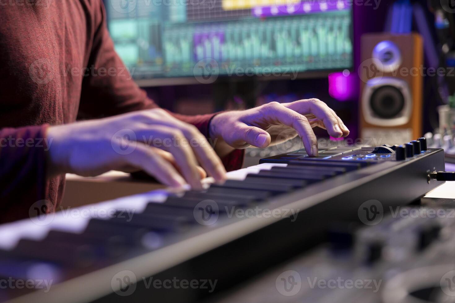 Artist playing piano notes and editing to improve the sound quality of audio recordings in home studio, handling electronic keyboard. Music producer uses midi controller to manipulate sounds. photo