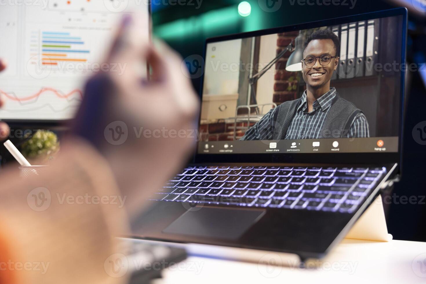 African american man talking on call using personal computer, discussing about accounting infographics. Young adult communicating online and examining monthly revenue balance. photo