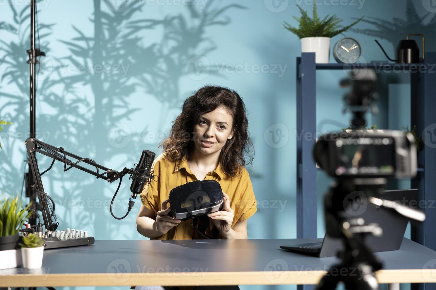 Futuristic VR goggles held by tech specialist reviewing them for viewers. Internet star filming technology channel vlog for gadget enthusiasts, showcasing virtual reality headset photo