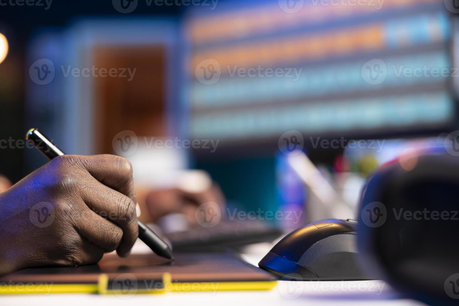 Black man photo editor in a well organized workspace editing images on dual monitors using advanced software tools, displaying creativity and professional dedication. Computer setup.