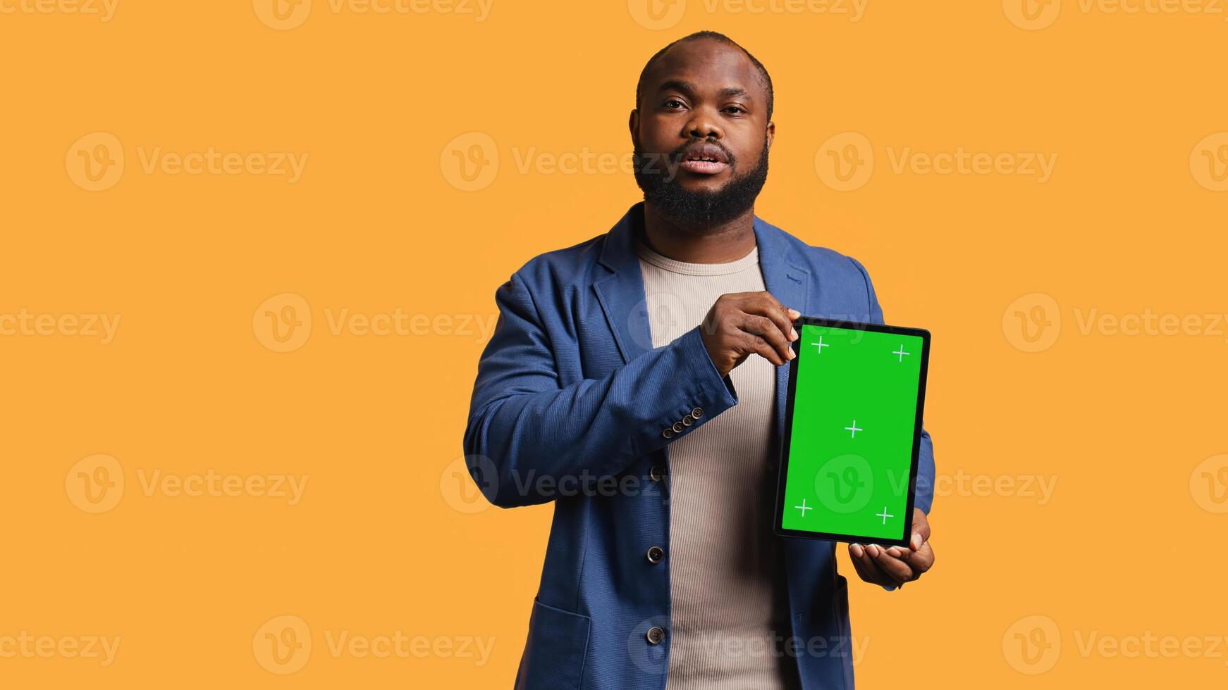 Portrait of african american man doing influencer marketing using green screen tablet, studio background. Smiling BIPOC person holding empty copy space mockup device, camera B photo