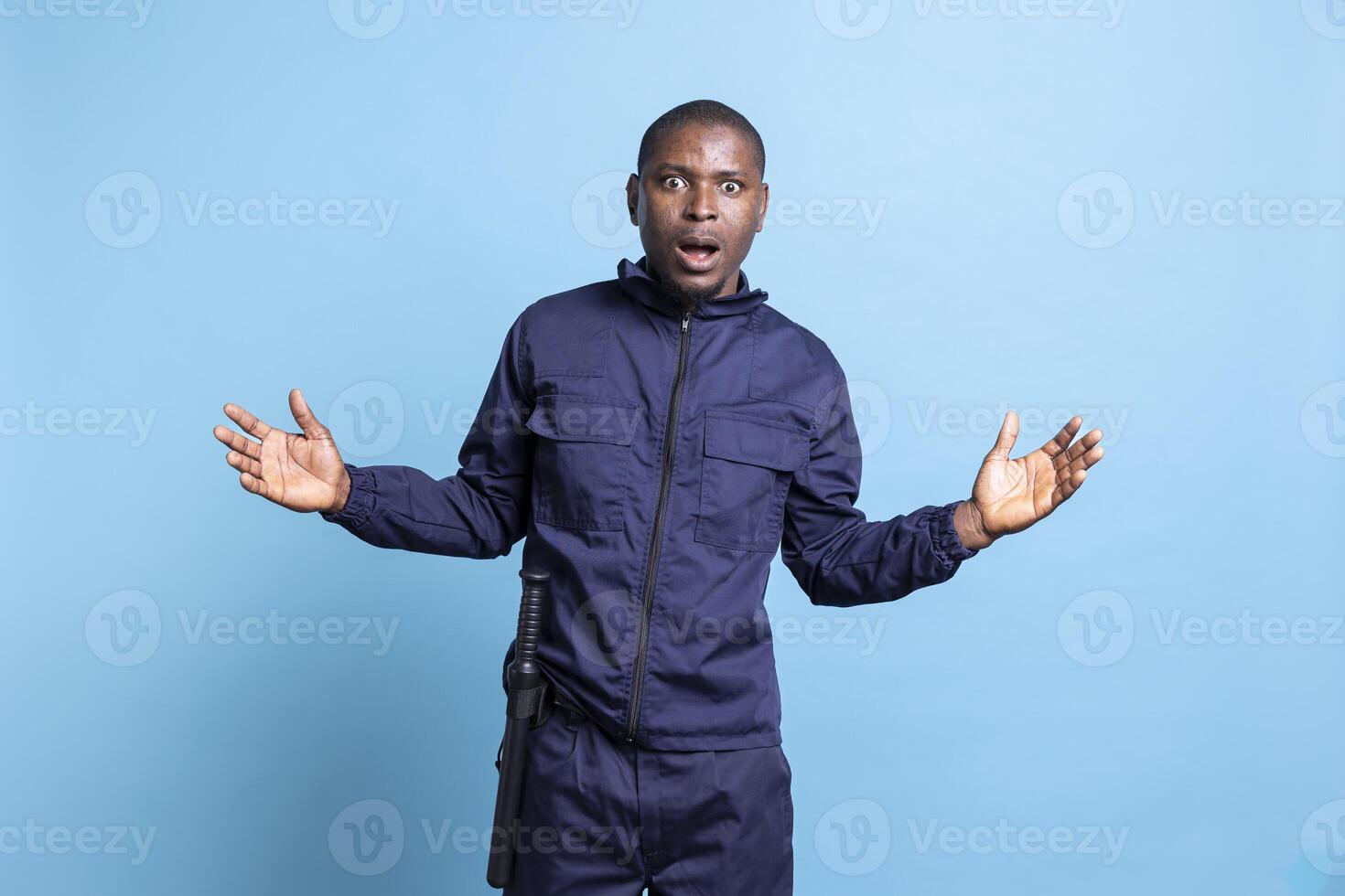 Security officer having a shocked reaction in front of the camera, being surprised after finding out something. African american public safety employee in uniform feels amazed in studio. photo