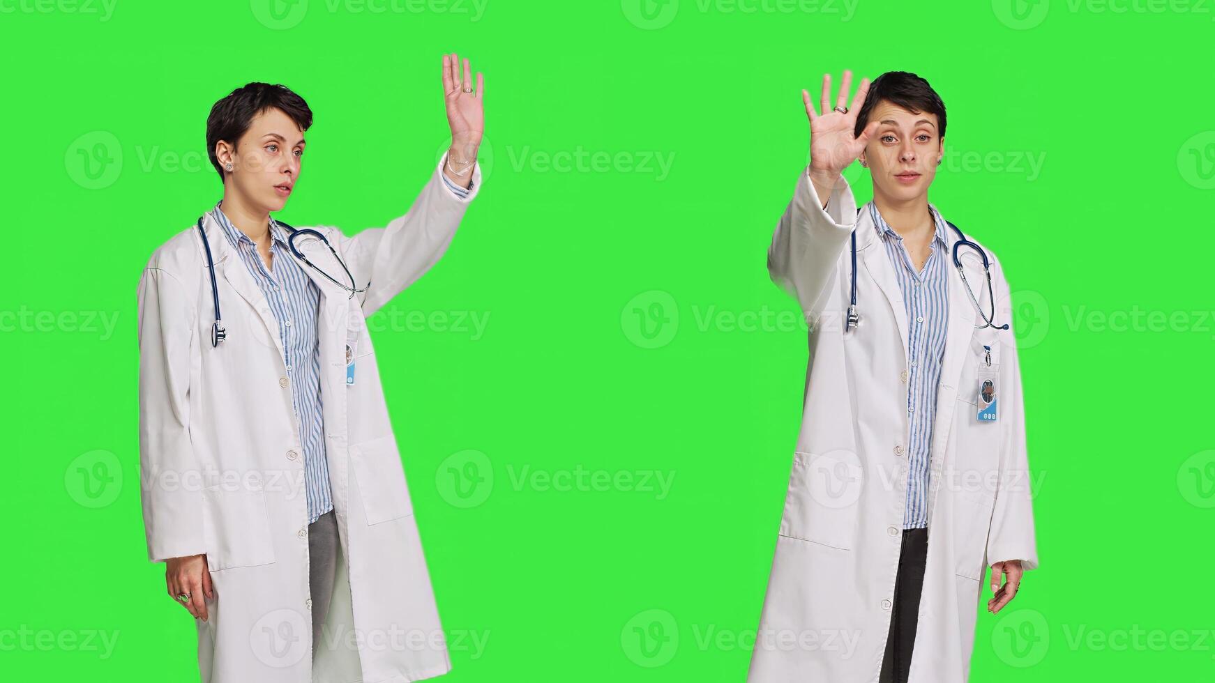 Woman medic waving hello and asking people to come over at checkup, inviting patient to come closer and greets them. Skilled physician with white coat and stethoscope against greenscreen. Camera B. photo