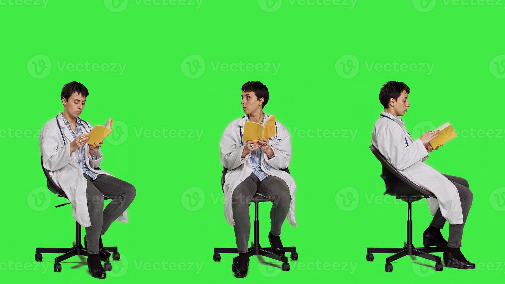 Medic specialist reading a medicine literature book sitting on a chair, enjoying healthcare industry lecture against greenscreen backdrop. Doctor in white coat reads for relaxation. Camera A. photo
