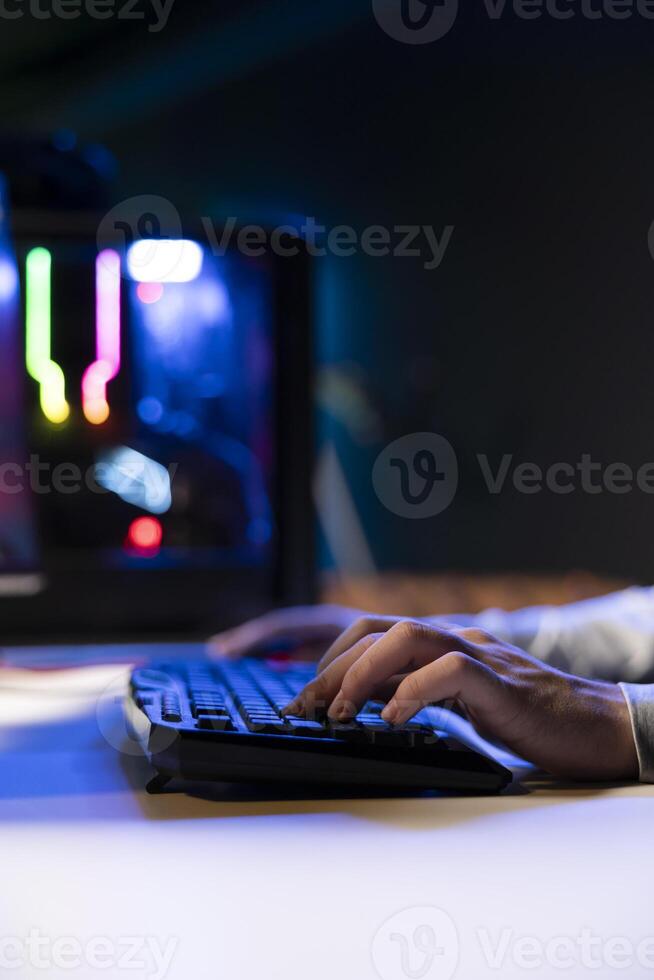 Man using keyboard to move character in game, playing with teammates online. Close up of gamer playing engaging games on gaming PC at computer desk, chilling after work photo