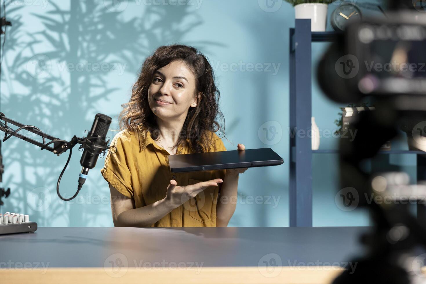 Smiling technology content creator filming review of newly launched thin gaming laptop. Upbeat internet star presenting notebook to subscribers, impressed by how sleek it is photo