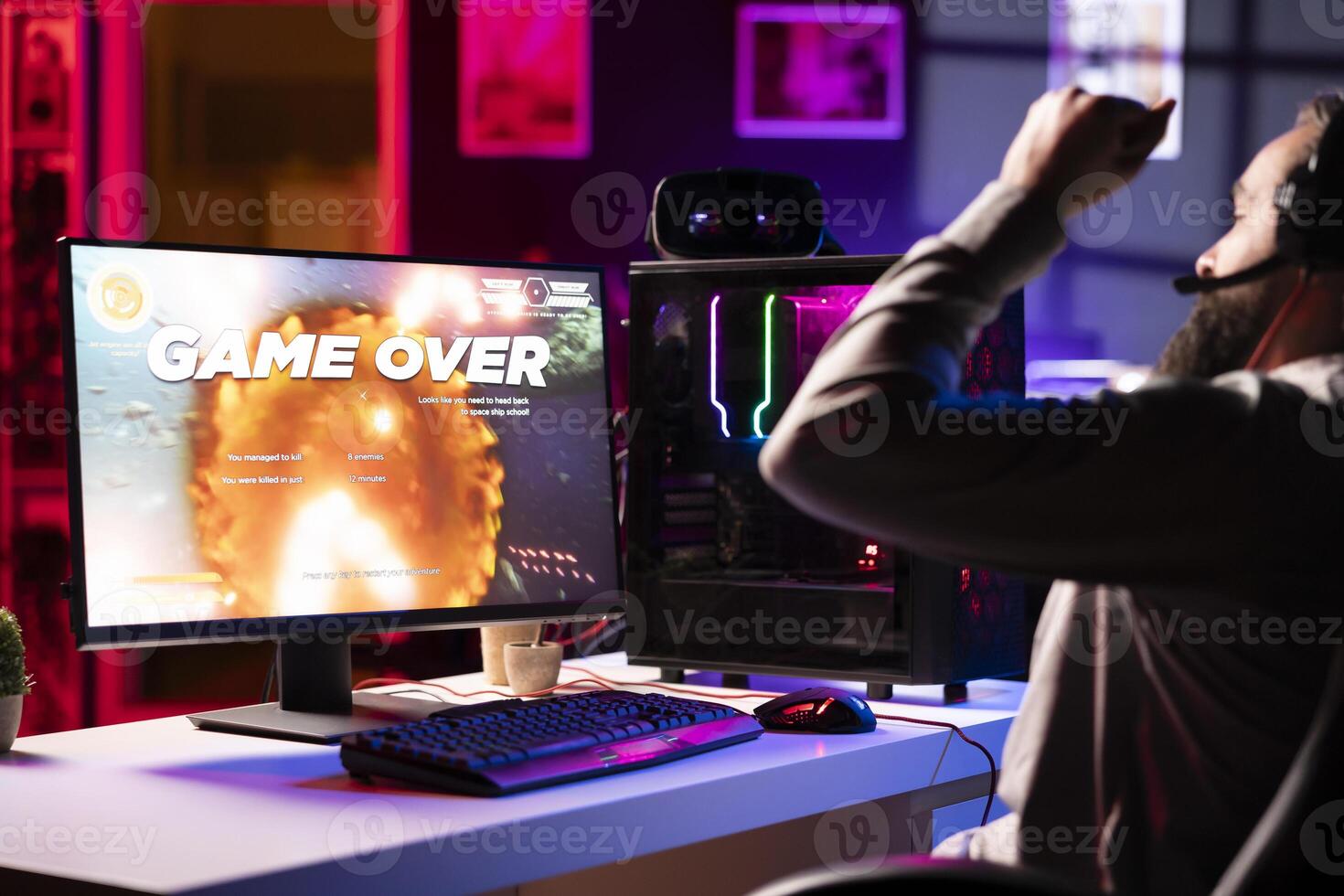 Upset gamer at desk frustrated after receiving game over screen, getting his spaceship destroyed in flying game. Sad player feeling gutted after losing science fiction videogame photo