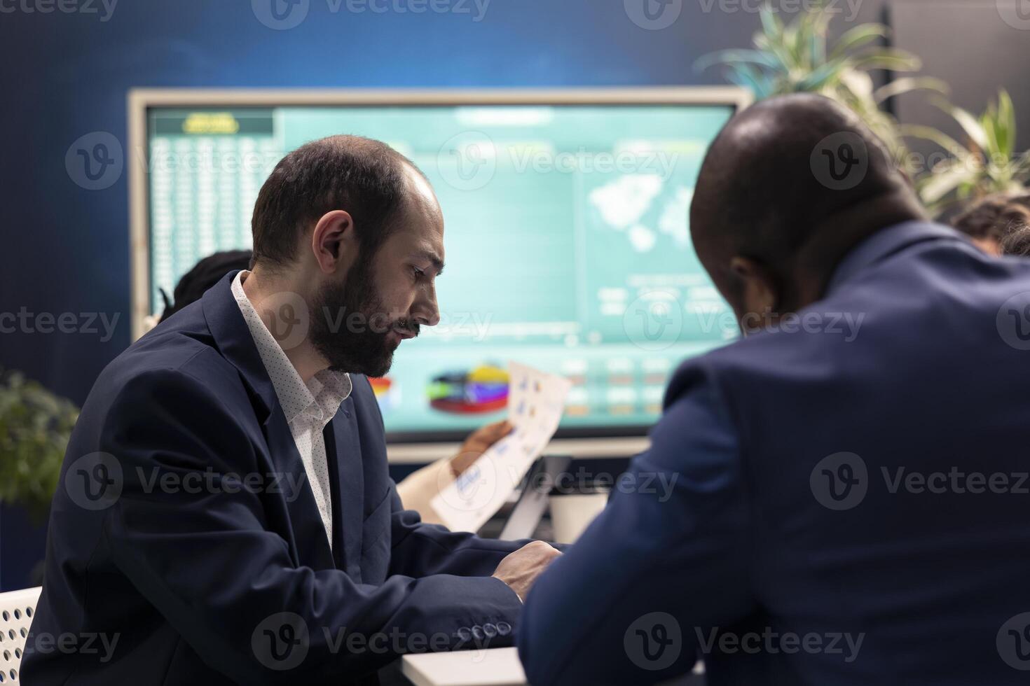 Public relations team develops marketing campaigns and promotional activities in a meeting, collaborating on new plans. Teammates reviewing sales trends metrics on documents, conduct analysis. photo
