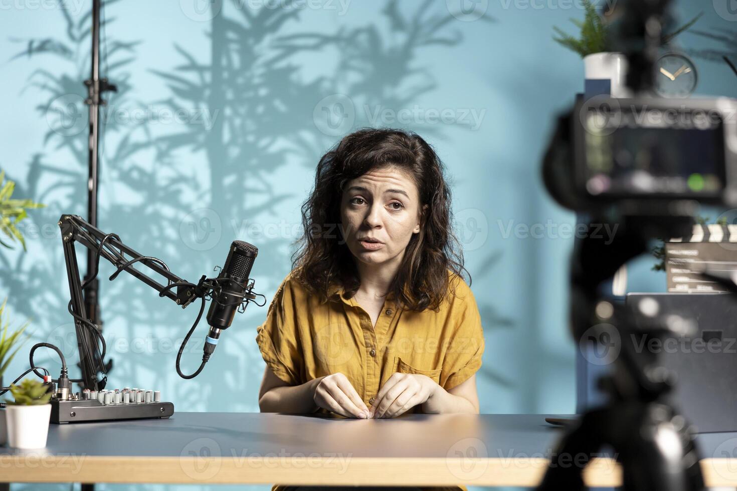 Upset influencer pouting while hosting internet show, speaking into professional mic, recording live stream with camera. Sad content creator frowning while engaging with audience photo