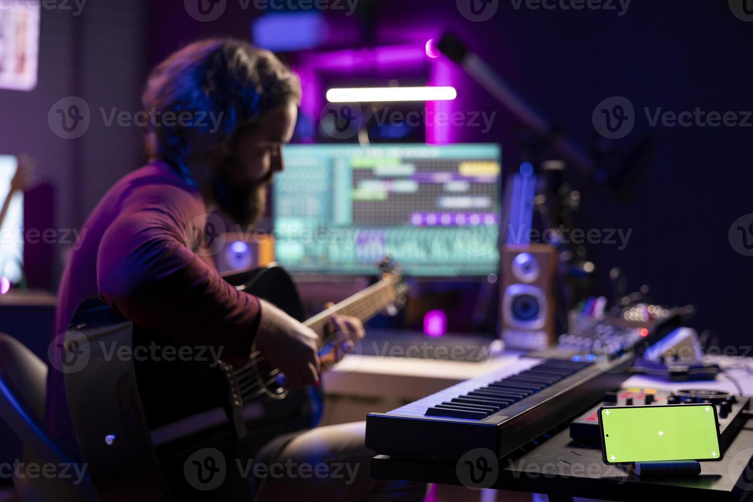 Young musician learning to play new accords on acoustic instrument, using greenscreen on smartphone display. Artist songwriter practicing guitar skills with online tutorials. photo