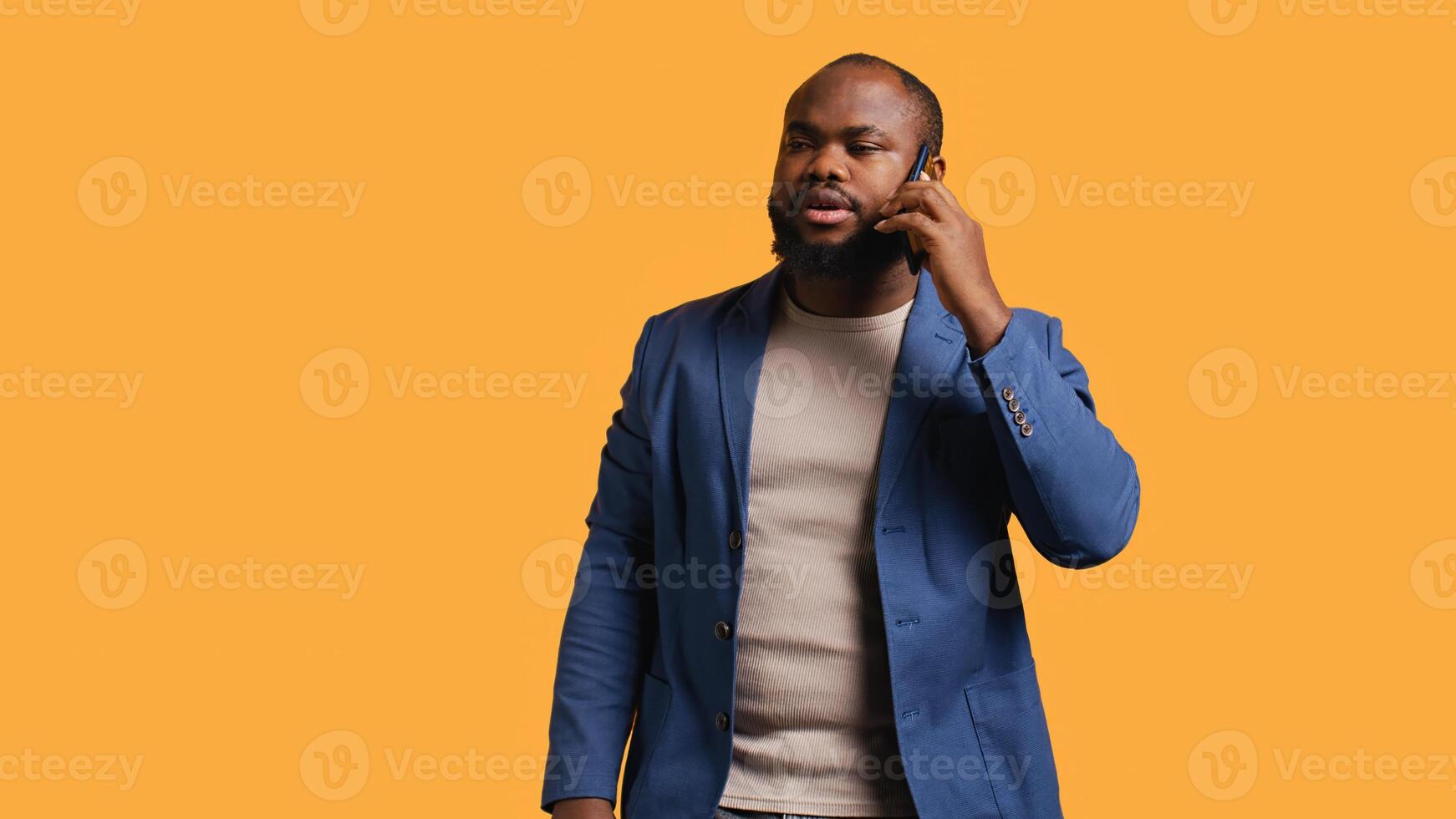 African american man having important phone call with business partner using smartphone, studio background. BIPOC person walking around discussing company matters during telephone call, camera B photo