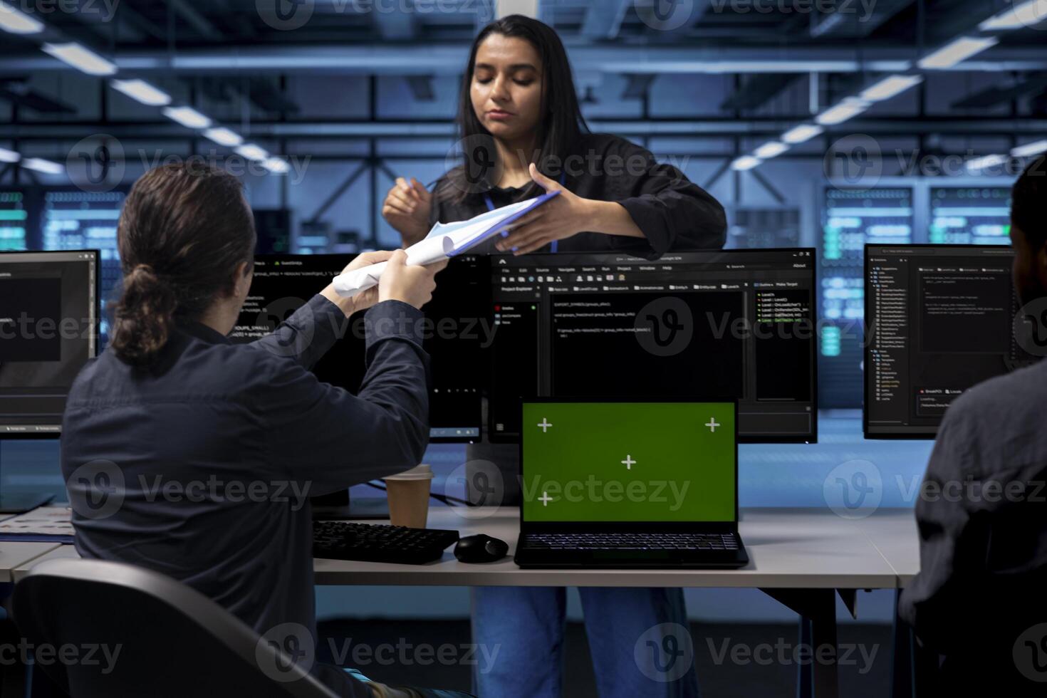 Woman inspects server hub, reading paperwork from folder, talking with workers working on green screen laptop. Supervisor evaluates data center and documents done by employees on mockup notebook photo
