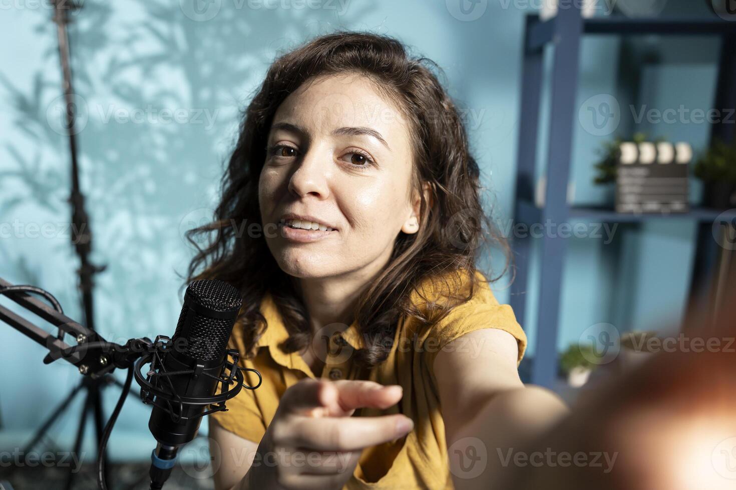 ASMR artist using quality mic and smartphone selfie camera in studio to do anti stress , whispering tingling sounds. Woman using microphone and mobile phone to film sleep inducing content photo