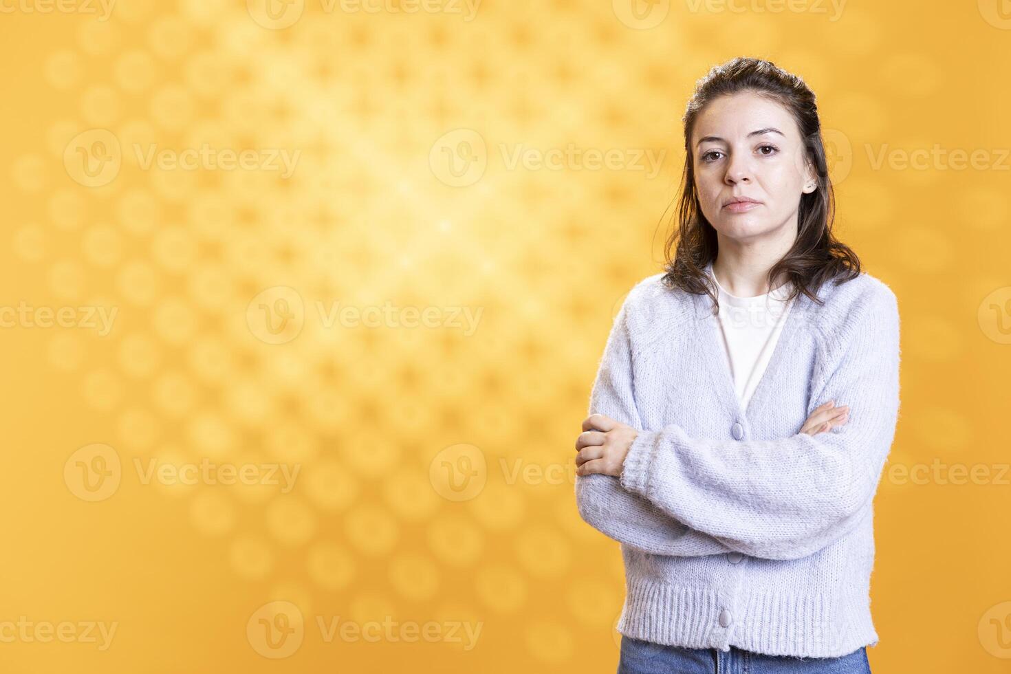 Portrait of woman crossing arms while posing, isolated over yellow studio background. Caucasian lady dressed in casual attire standing, looking at camera, feeling confident photo