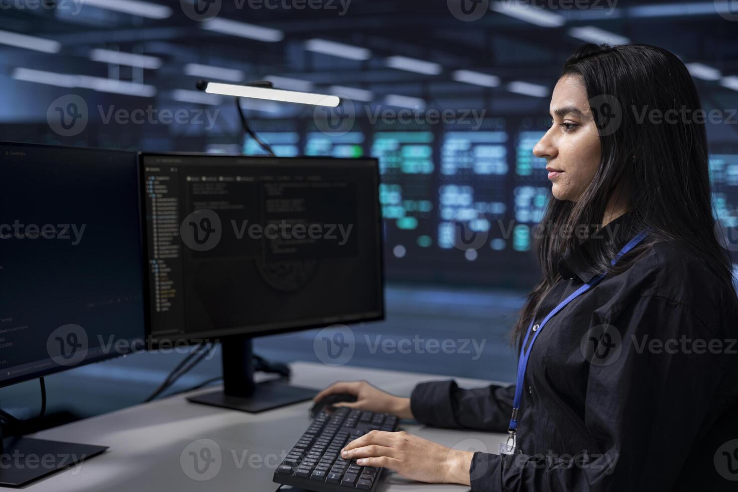 Software programmer in server farm tasked to oversee mainframes devices used for managing databases. Indian woman in data center establishment doing checkup on rackmounts storing information photo